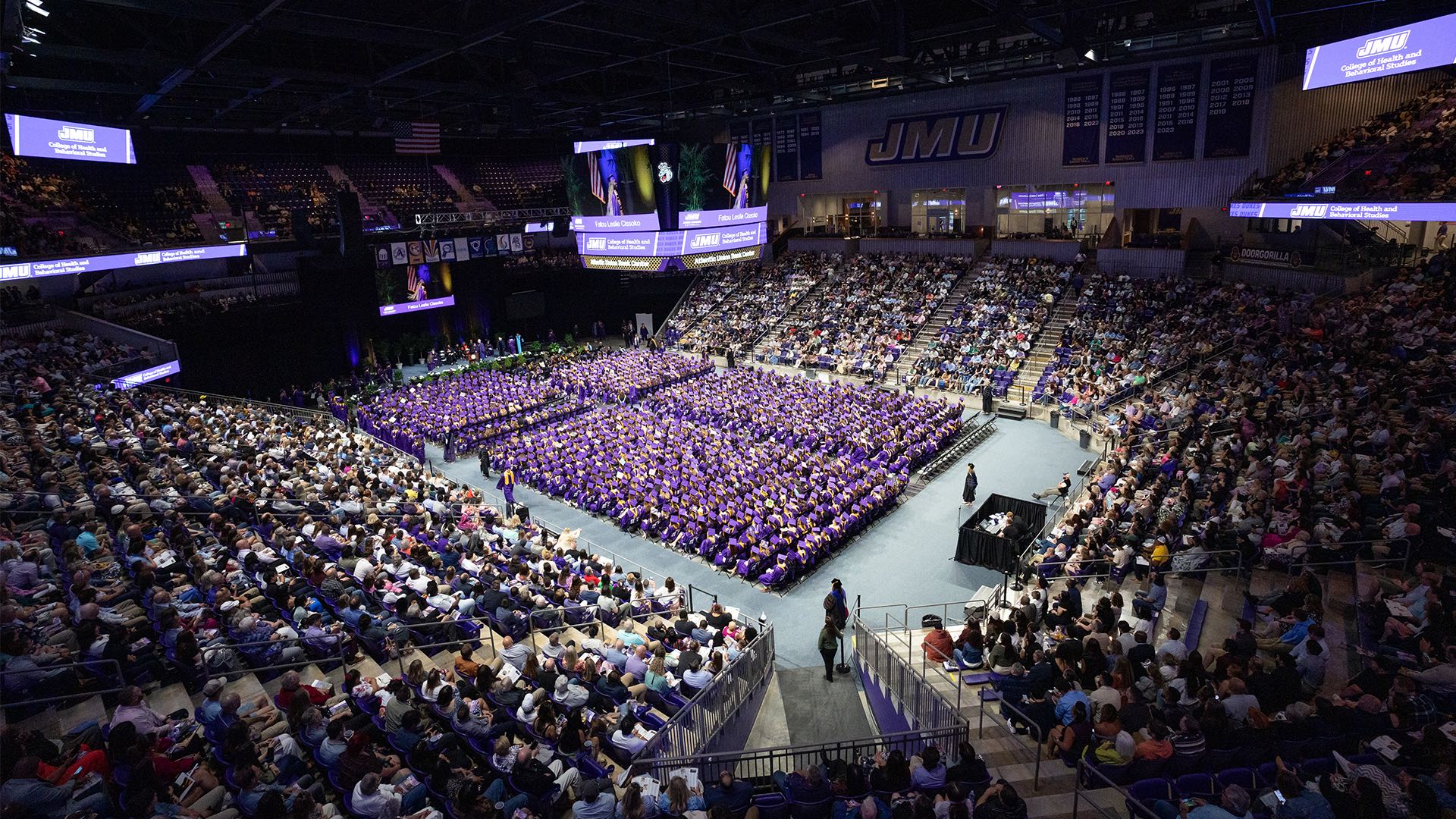 JMU graduation ceremony - full arena view with thousands of graduates in purple