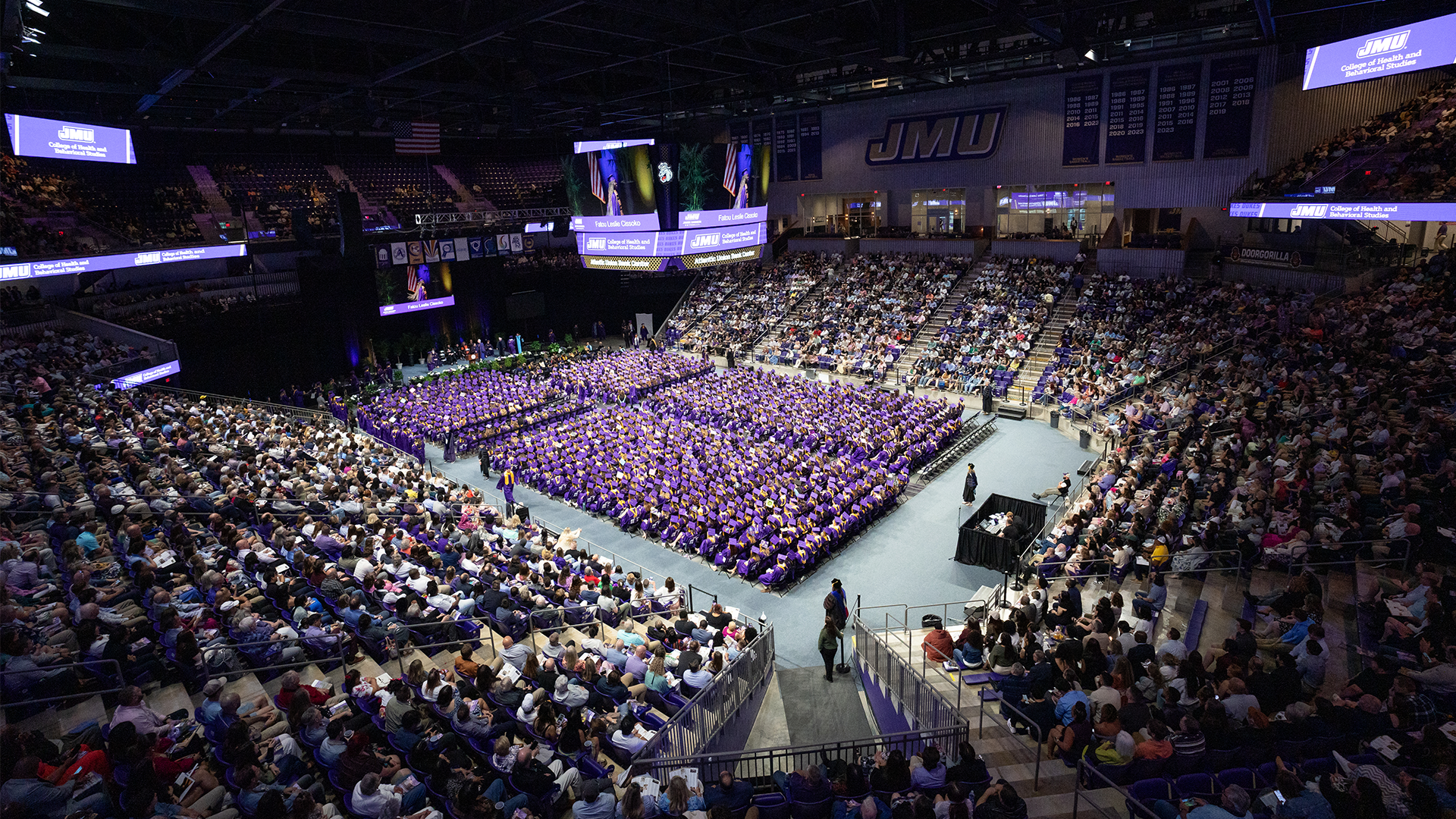 JMU graduation ceremony - full arena view with thousands of graduates in purple